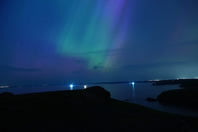 Green and purple shafts of light coming from the sky