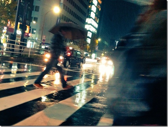 雨の夜に横断歩道を渡る男性
