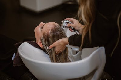 Peluquera aclarando el cabello a una clienta en el lavabo