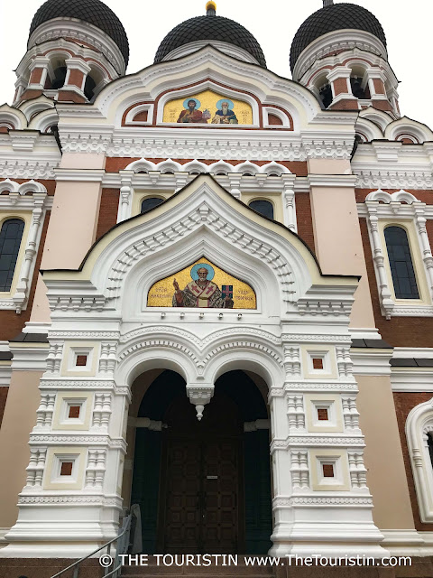 The distinct facade of a red brick Russian Orthodox church with three onion domes.