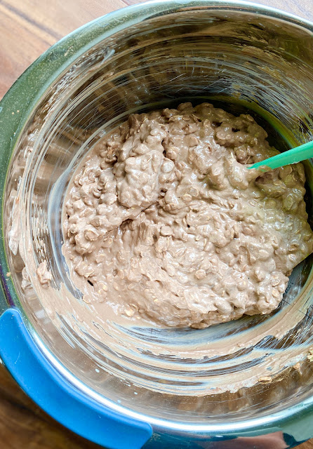 Stainless steel mixing bowl with spatula and brownie oatmeal batter.