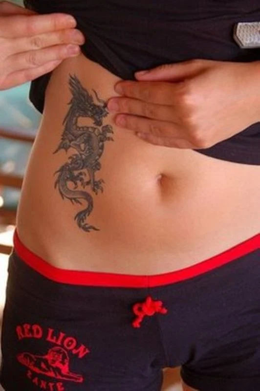 vemos a una mujer posando luce el tatuaje de un dragon