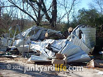 A midseventies Corvette and a 1968 Impala convertible rest beneath this