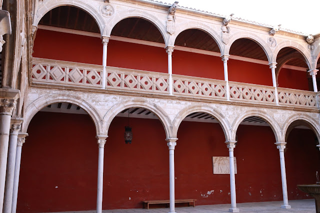 Claustro con galerías pintadas de rojo y arcos y columnas blancas.