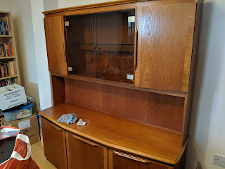 A dresser, or sideboard (depending on who you ask) with three cupboards and a full surface on the lower portion, and a raised upper portion with two wooden cupboards and a glass-fronted cupboard with two doors.