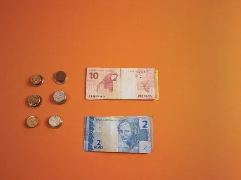 Gif animada mostrando uma pessoa colocando notas de dinheiro sobre uma mesa cor laranja