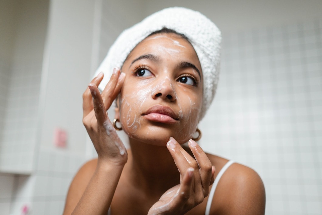 A young woman wearing bathrobe standing in the bathroom washing face