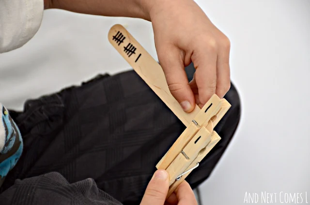 Closeup of a child clipping wooden clothespins onto a tally mark stick