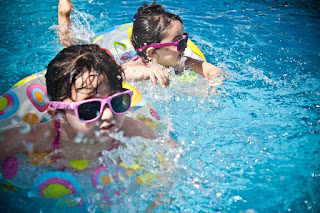 Image of toddlers swimming with a noodle. Swimming for newborns prepares well for this.