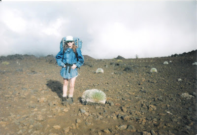 rather young looking human with an external frame backpack, oversized jacket, and almost vanished shorts