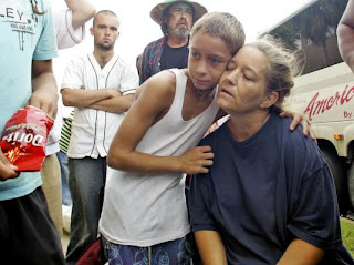 Matthew Harris, 12, hugs his mother Karen Harris as they wait in line to board a bus that will take them out of Galveston September 13