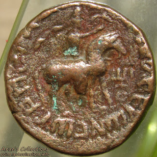 King in Iranian cap with logn diadem-ties riding on horse to right holding axe-like weapon in raised right hand, three-pronged tamgha on right. Greek legend around.