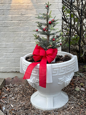 christmas tree in an urn planter with decorations and bow