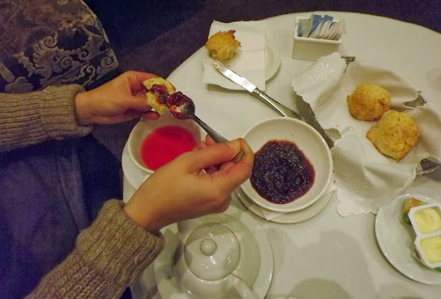 mão colocando compota em scone numa mesa de chá das 5