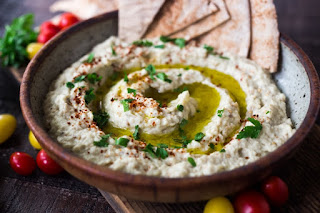 A bowl filled with baba ganoush topped with parsley and drizzled in olive oil.