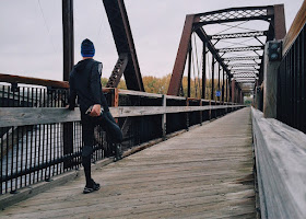 Man on bridge stretching, preparing to run