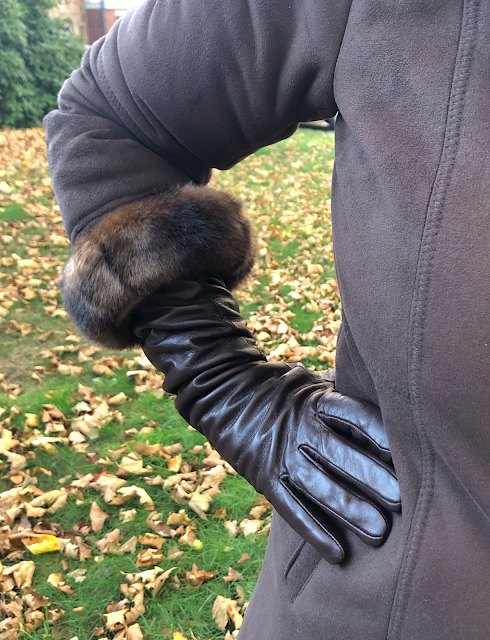 woman wearing coat with arm bent to show long leather gloves covering forearms