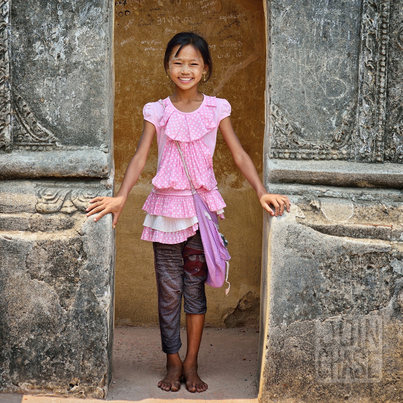 A smiling girl under an arch on top of Shwegugyi Temple in Bagan, Myanmar.