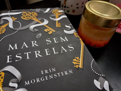 Foto do livro "O Mar sem Estrelas" em uma mesa ao lado de uma vela