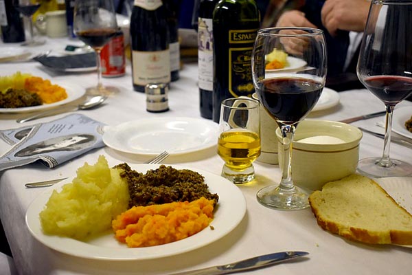 close-up on a table with wine bottles and glasses, and unidentifiable mashed food on plates