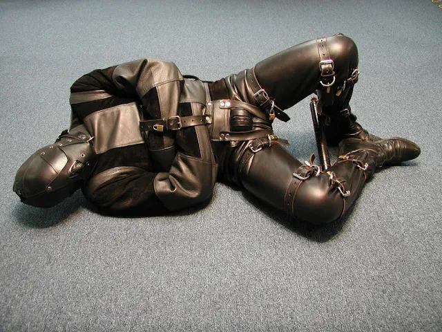 10/12 man bound completely in leather with a hood, leather straitjacket while he finally rolls around on the floor