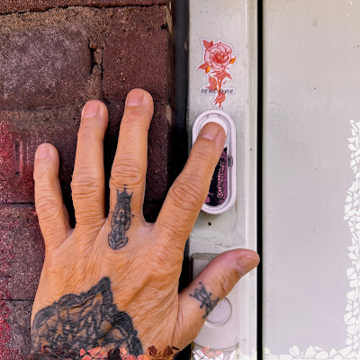 Getatoeëerde hand met vinger die op deurbel drukt