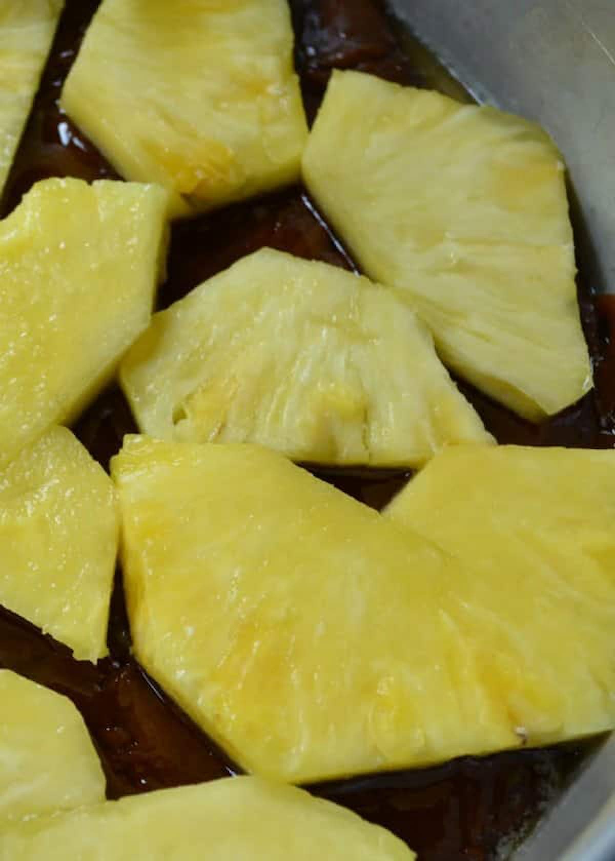 Caramelized Sugar topping placed into a cake pan and topped with fresh pineapple slices.