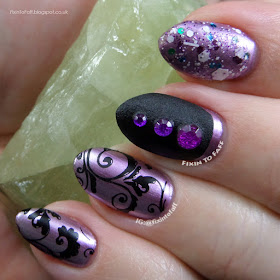 Nail art featuring stamping, glitter, texture, and rhinestones over chrome polish in purple and black tones.