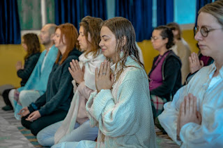 Several women sitting in a temple cross-legged in prayer