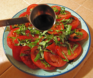 Hand with Tablespoon Sprinkling Balsamic on Tomatoes