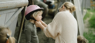 A woman wearing a helmet to a child