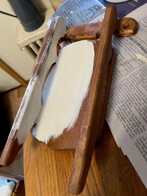 Photo of a small wooden sled being painted with off white chalk paint.
