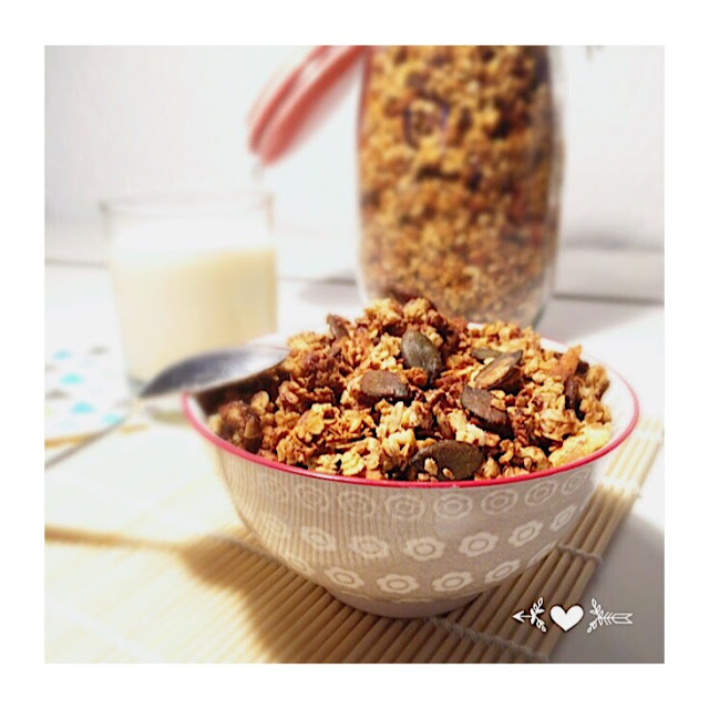 alt="bol de granola avec en arrière plan un verre de lait et un pot de granola"/