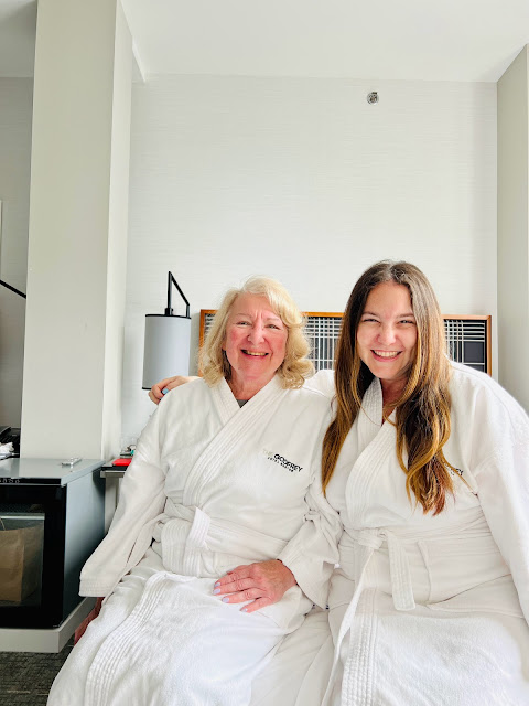 Jamie Sanders and her mom sit in a hotel room at the Godfrey Hotel Boston wearing Frette robes.