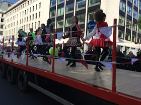 Pic of young Irish dancing on float holding hands as they dance in line facing opposite directions