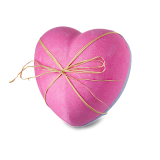 A neon pink heart shaped bath bomb split into two filled with red and white flowers tied with pink string on a bright background