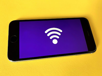 Smartphone con una pantalla en morado con un símbolo de WiFi sobre una superficie amarilla