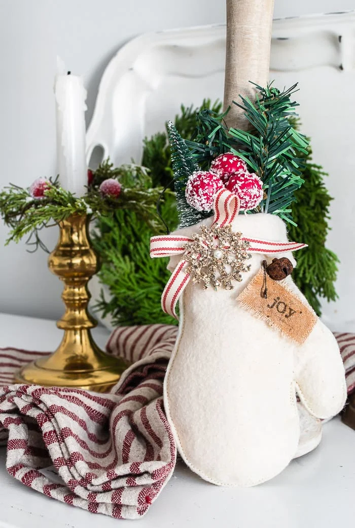 mitten ornament, red striped cloth, brass candlestick, greenery