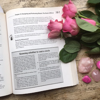 Open book displayed with some pink roses and crystals