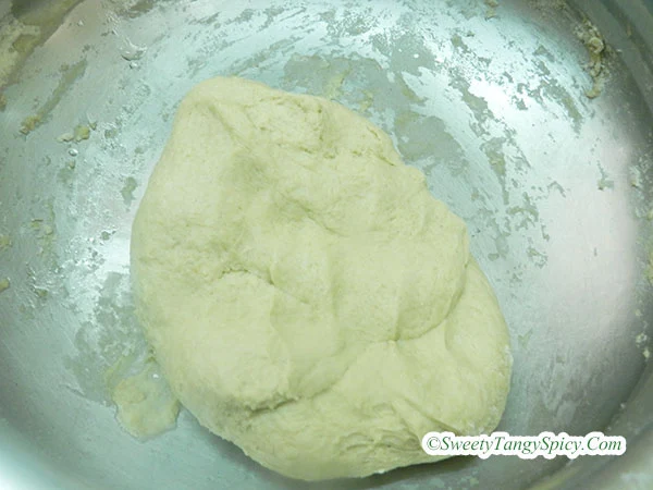 Hands kneading chapati dough to achieve a soft and pliable texture, showing the transformation from the original color to a lighter shade.