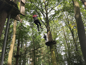 daughter on a zip line into a cargo net in the trees go ape matfen