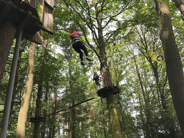 daughter on a zip line into a cargo net in the trees go ape matfen