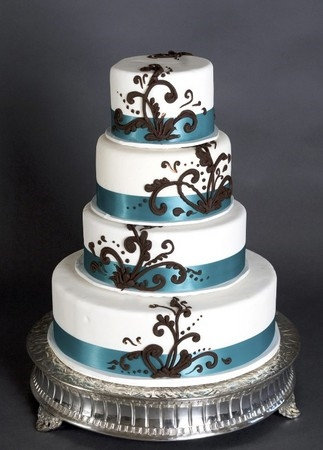 Four tier white round wedding cake with blue satin ribbon and brown
