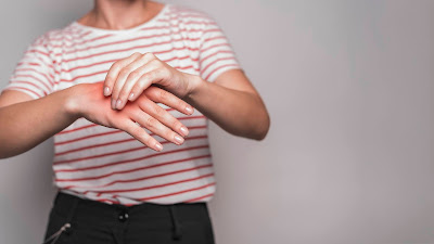 a white person holding their slightly reddened right hand when their left, suggesting pain