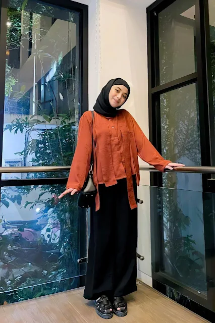 Tania Dewi Nur Azmi wearing terracotta-colored shirt with a hijab and black culottes, looking stylish paired with a shoulder bag and strap shoes
