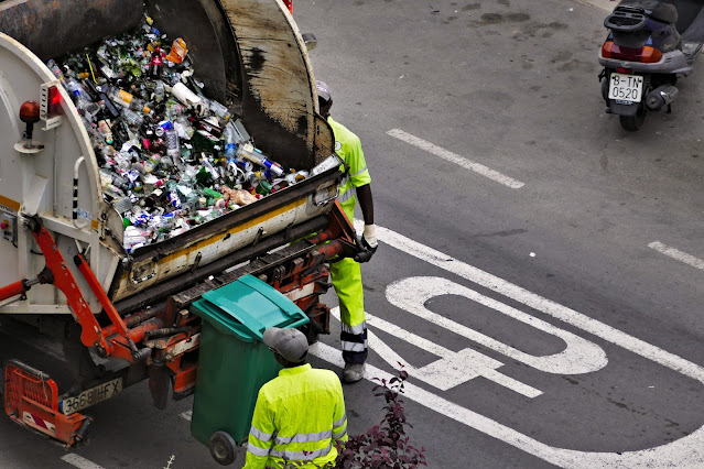 Sanitation workers filling a truck with garbage