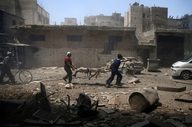 Men transport a casualty at a site hit by airstrikes in the rebel held Douma neighbourhood of Damascus, Syria