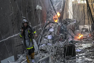 A Palestinian firefighter works at the site of a destroyed building after Israeli airstrikes in Gaza