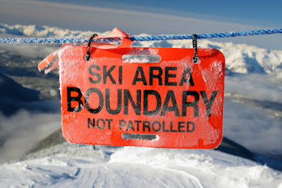 A sign in the mountains reads "Ski Area Boundary-Not Patrolled"