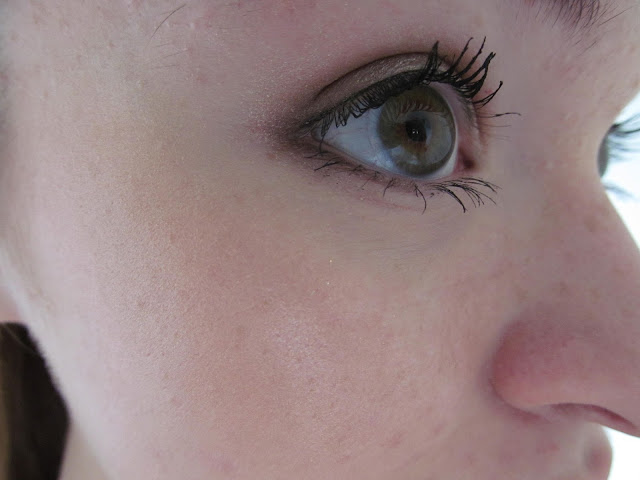 close up of hazel eye looking forward with subtle shimmer eyeshadow, black top eyeliner and mascara, contact lens visible